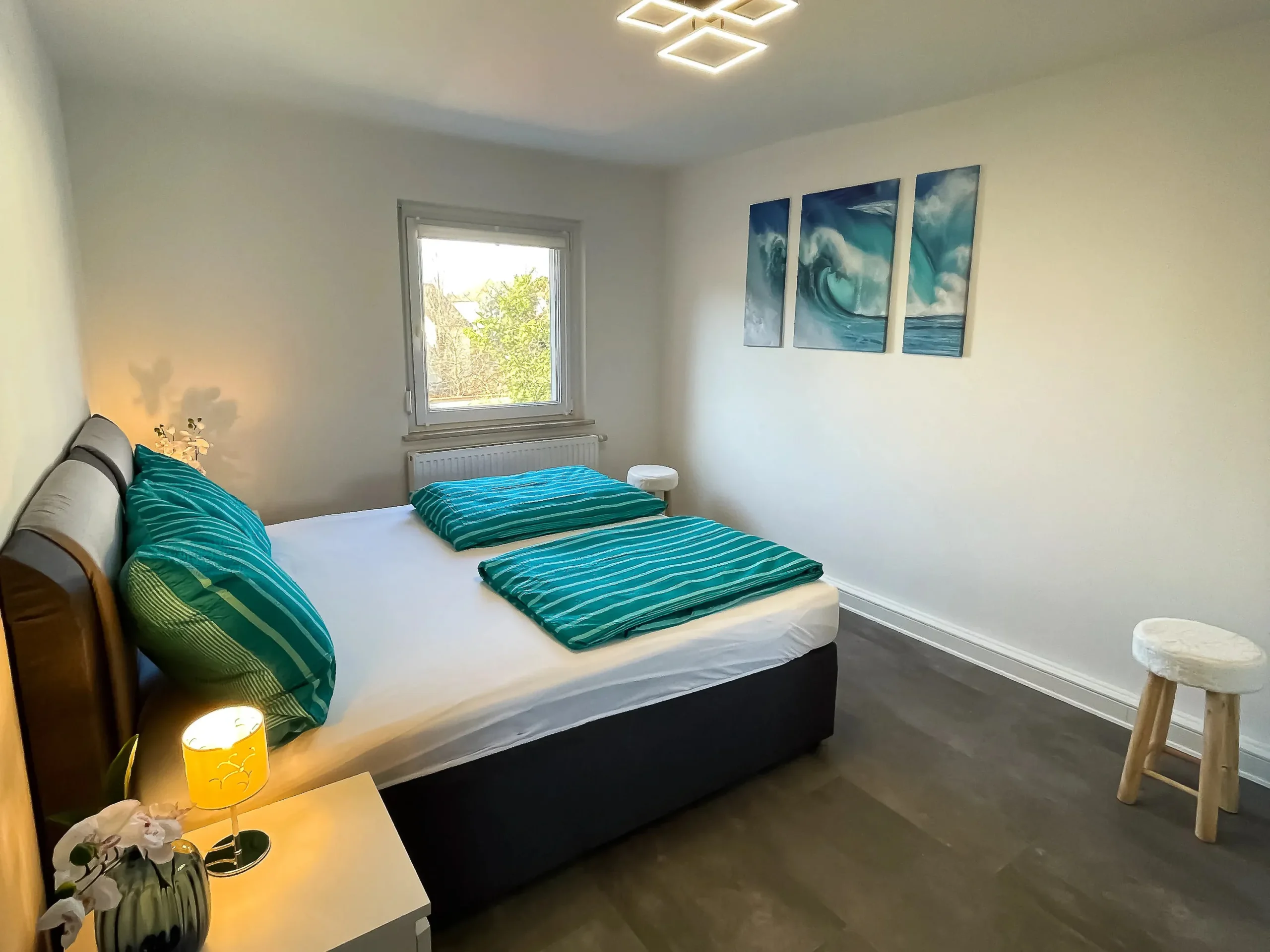 ferienwohnung-halle-schlafzimmer-wellenbilder-hocker